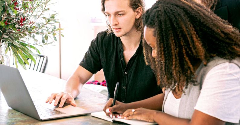 Project-Based Learning - Man Working on Laptop while Woman Takes Notes