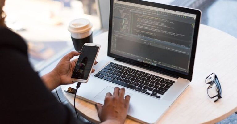 Remote Working - Person Holding Smartphone while using Laptop