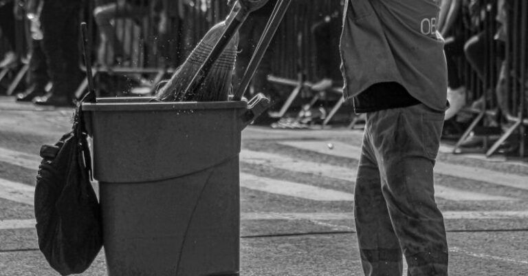 Language Barriers - A man is pushing a trash can down the street