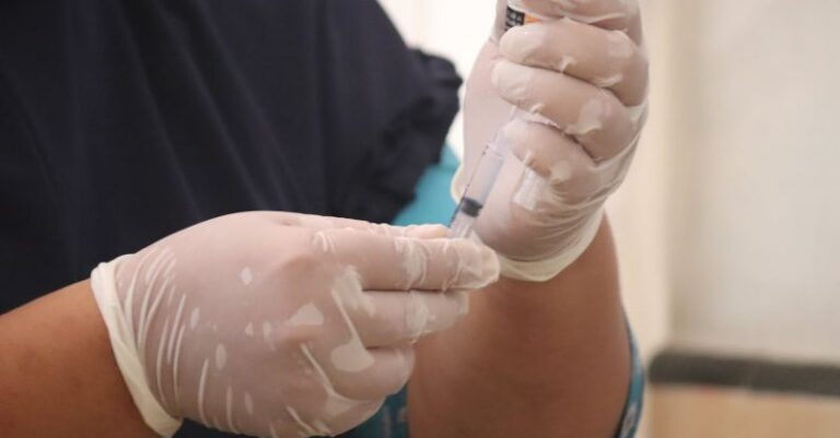 Injury Prevention - Person in Black Scrubs and White Latex Gloves Holding Syringe